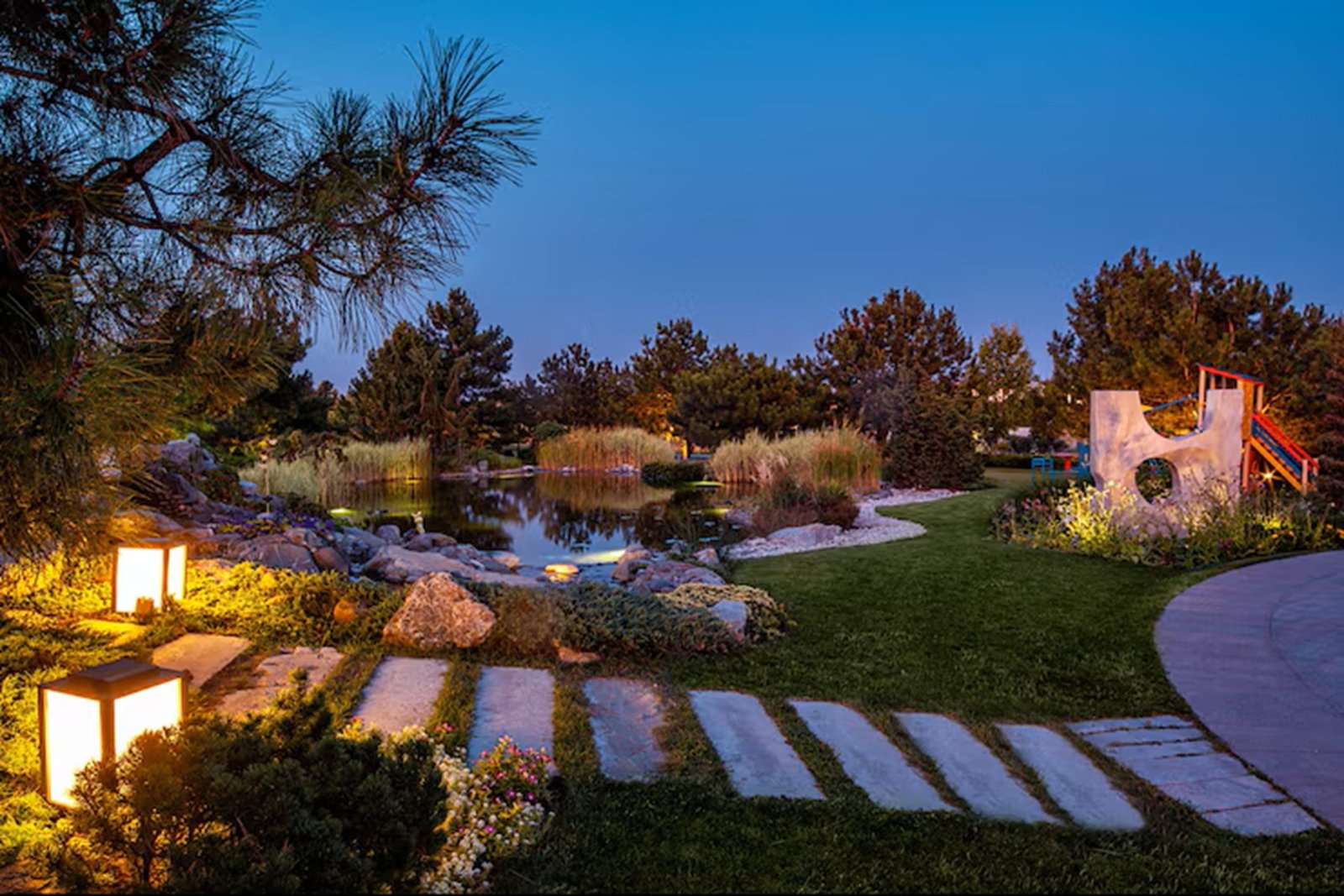 evening-summer-view-park-with-pond-children-playground-flower-beds-cobbled-paths_157927-6749